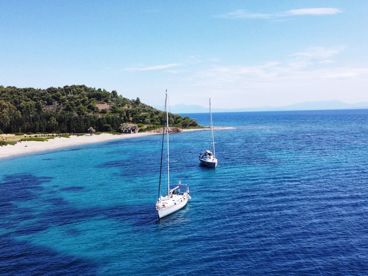 Two sailing boats anchored off a Greek beach