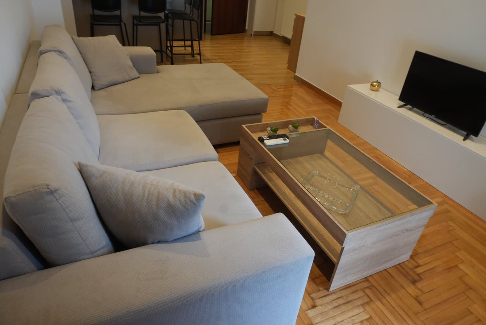 The living room of one of the apartments, with a corner sofa and parquet floor